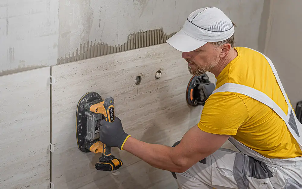 AM Raumbau Berlin GmbH Ein Arbeiter verlegt eine große Wandfliese