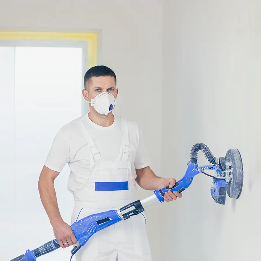 Ein Arbeiter mit Schutzmasken glättet eine Wand