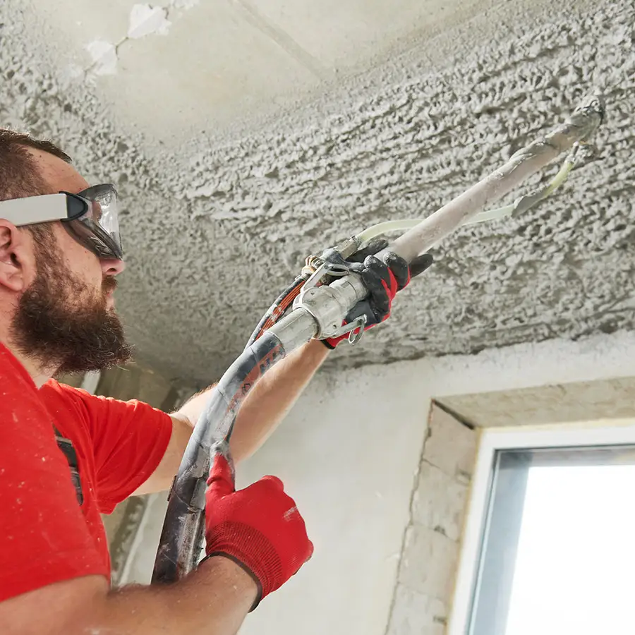 Ein Arbeiter sprüht Putz auf eine Decke